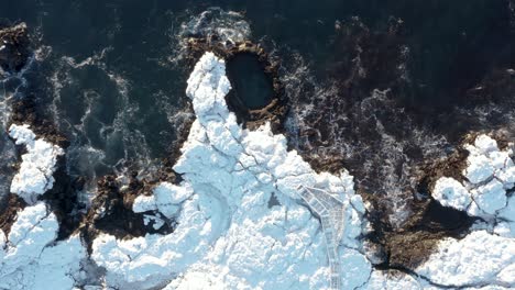 above tourist attraction rock pool brimketill on snowy shore of iceland