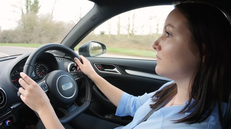 Giovane donna alla guida di un'auto, vista laterale