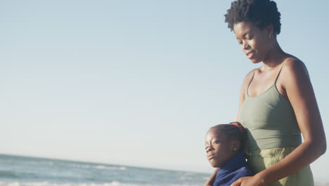 happy african american mother and daughter embracing at beach, in slow motion, with copy space