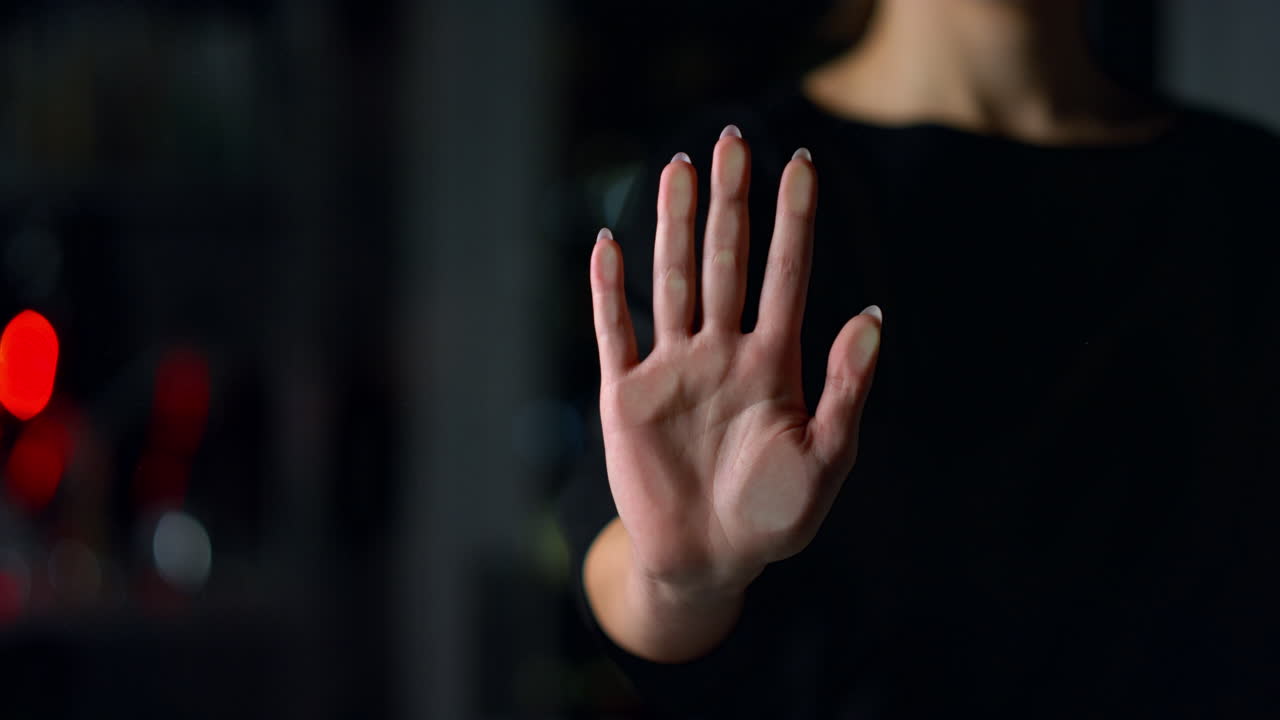 실내에서 유리 벽을 만지는 여성 손의 클로즈업. 소녀가 손자국을 남긴다.