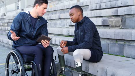 two disabled athletics discussing over digital tablet 4k