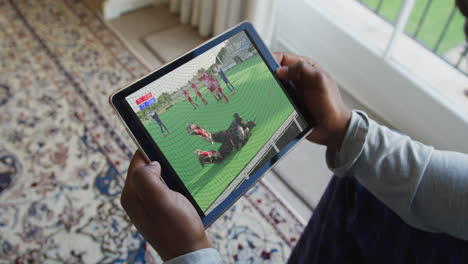 compuesto de un hombre sentado en casa, viendo un partido de hockey en la tableta