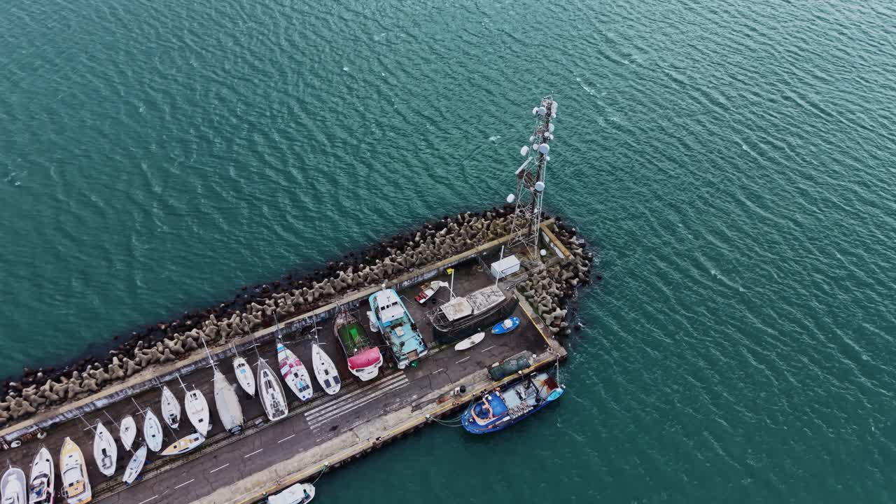 Barche attraccate in un porto con una torre di telecomunicazioni vicino al mare