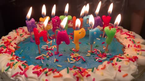 niño soplando las velas de un colorido pastel de cumpleaños