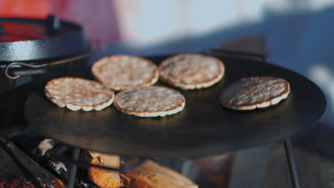 traditional hällakakor flatbread baking on flat log fire stove plate, sweden