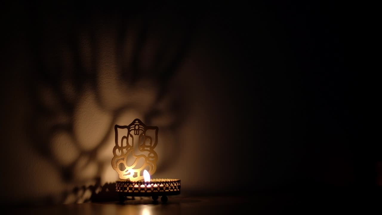 Static side shadow and light dance, play reflection on wall of Ganesha cutout, also Ganapati Vinayaka, one of the best-known and most worshipped deities in the Hindu pantheon, specially during Diwali