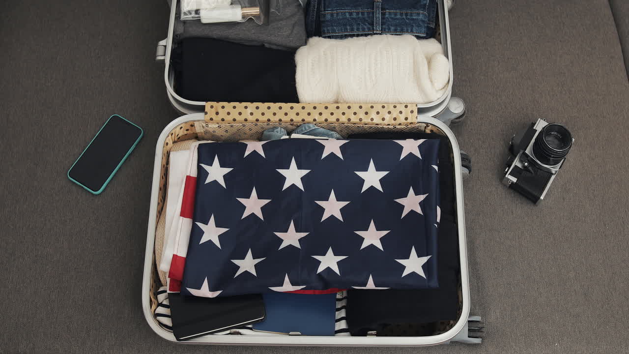 Suitcase packed with American flag, clothes, and camera