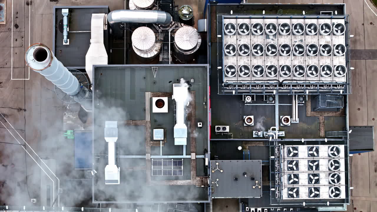 Aerial ascending birdseye drone shot above industrial power plant with cooling fans, smokestack and energy infrastructure