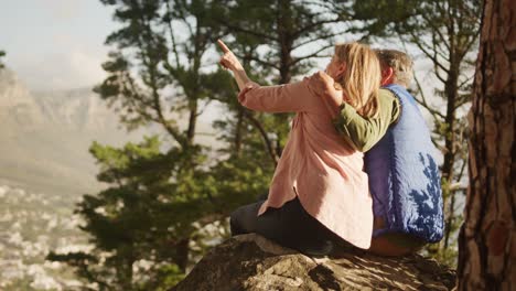 Active-senior-couple-sitting-on-rock-in-forest