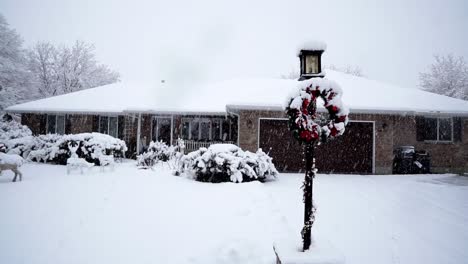 cozy suburban house covered in snow and heavily decorated for christmas with lights, wreaths, and fake deer