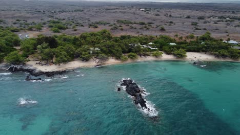 toma cinematográfica de drones en sentido antihorario de 4k de la playa de waialea y la isla de roca de lava que está presente dentro del agua