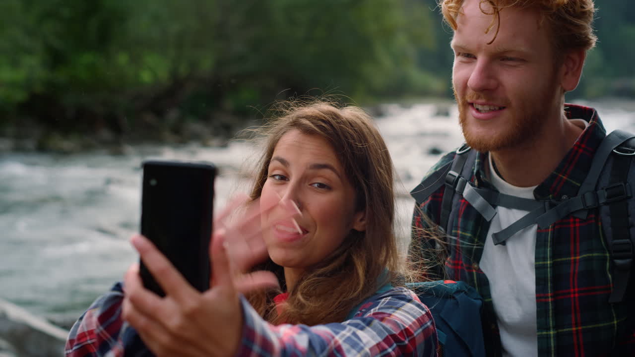 pareja agitando las manos a la cámara durante el chat de video. excursionistas usando teléfono móvil