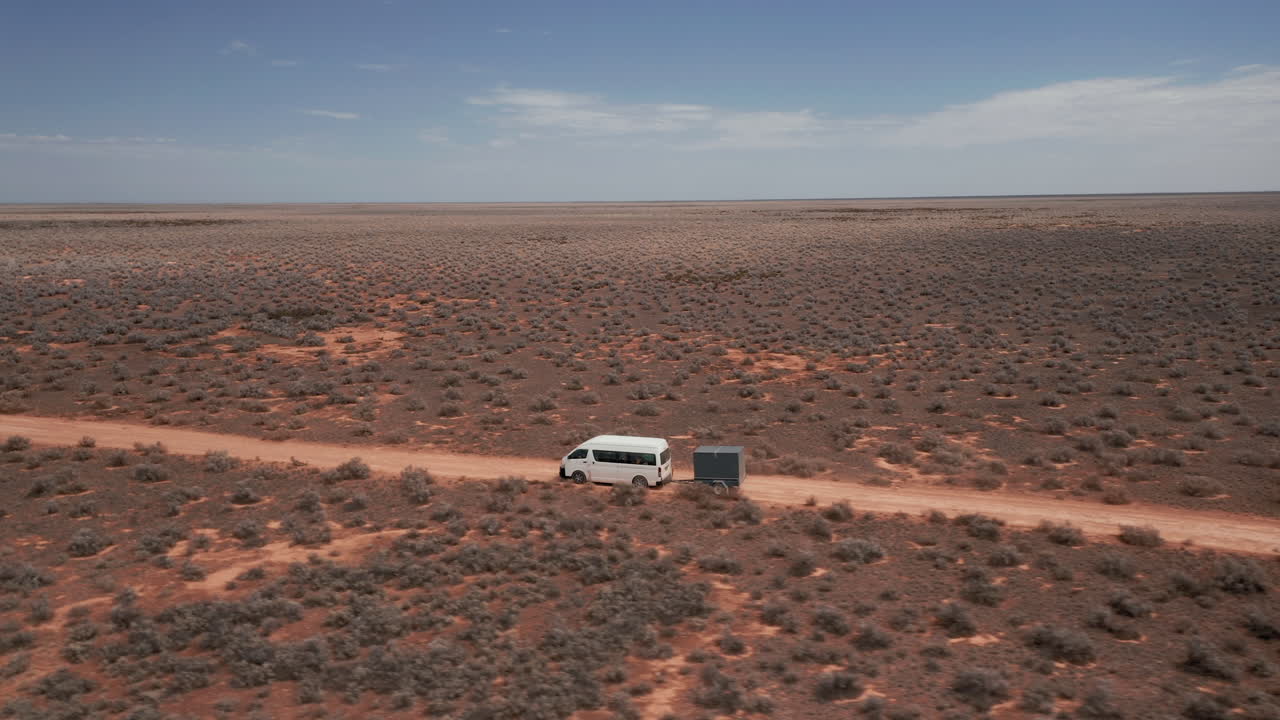 Aerial view following a camper and a trailer, sunny day, on a desert, in Australia - orbit, drone shot