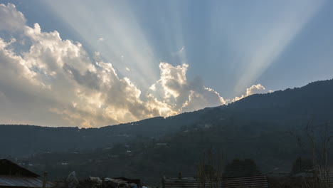 雲彩的夜晚時間流動 當太陽在山下面落下 美麗的金色太陽射線與雲彩跳舞