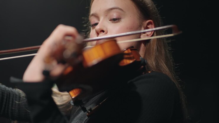 female fiddler in symphonic orchestra on scene of opera house lady is playing violin or viola