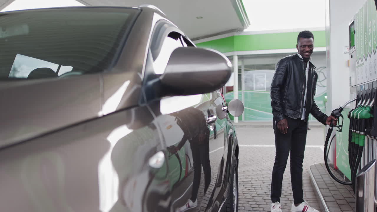 Eine Zapfpistole wird an ihren Platz gebracht: Ein stilvoller Afroamerikaner tankt an einer Tankstelle sein Auto