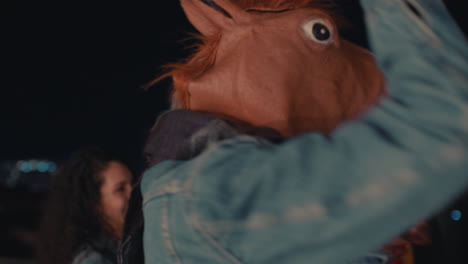 happy group of friends dancing having fun man wearing funny horse mask enjoying crazy rooftop party at night celebrating friendship