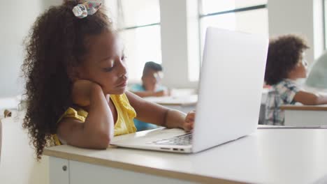 Video-Eines-Gelangweilten-Afroamerikanischen-Mädchens,-Das-Während-Des-Unterrichts-Im-Klassenzimmer-Mit-Einem-Laptop-Am-Schreibtisch-Sitzt