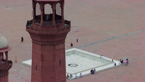 lahore, pakistan, close up zooming out aerial view of minarets of the world famous badshahi mosque, visitors ladies, gents and children are in the mosque, worshipers in the ground of the mosque