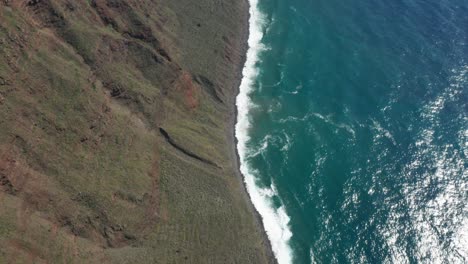 steep sloped shoreline at madeira with vivid blue ocean water, aerial