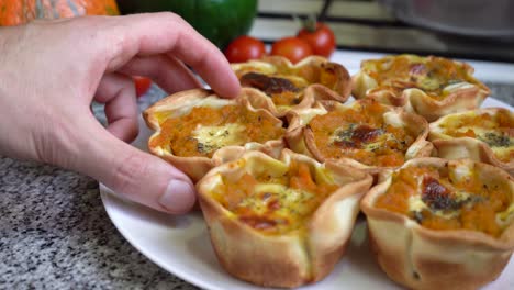 hand takes a piece of pumpkin tartlet and puts it back on the plate