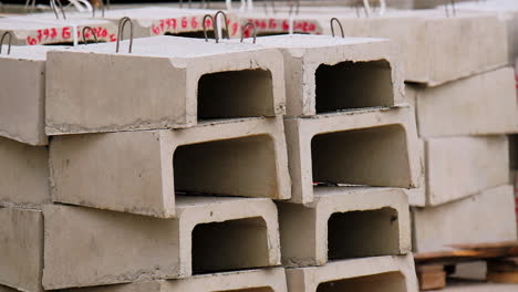 grey arched cement blocks with metal loops on top. materials for construction placed on wooden pallets outdoors.