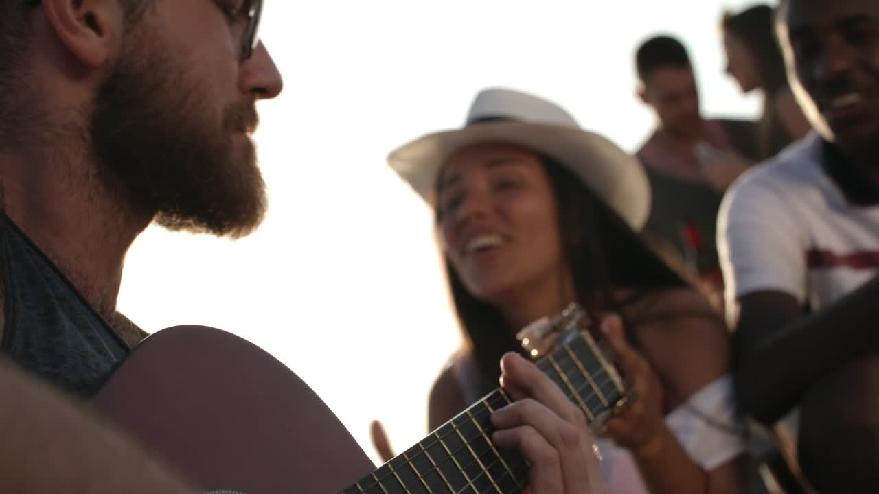 hombre tocando la guitarra y cantando con amigos