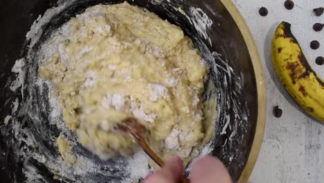 4k top view stirring ingredients in large bowl with bananas and chocolate chips