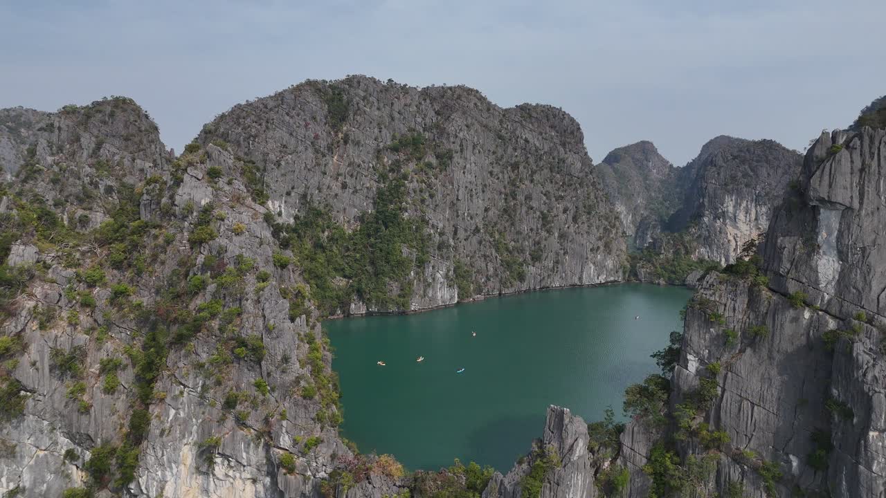 Drone video captures Ha Long Bay's striking limestone cliffs and emerald waters under clear skies. The serene aerial view highlights natural beauty, tranquility, and vibrant hues