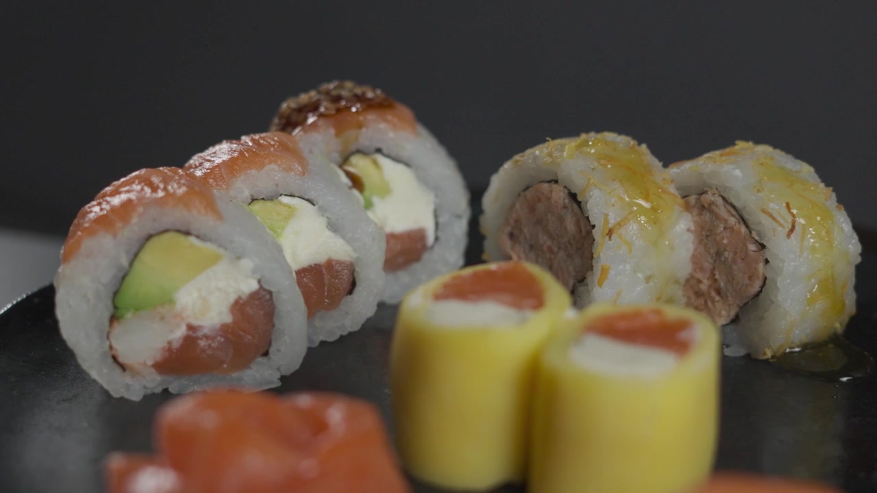Koyu renk tabakta çeşitli taze Japon suşi ruloları yakın çekim