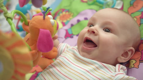 Close-up-of-little-boy-face.-Portrait-of-happy-baby-on-colorful-mat-with-toys