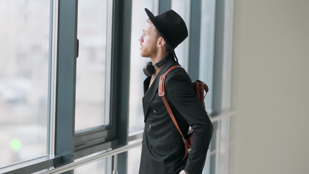 세련된 잘생긴 곱슬머리 남자는 모자를 쓴다