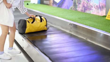 traveler retrieves bag from airport conveyor belt