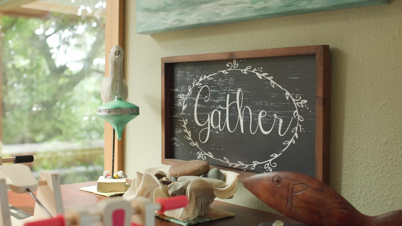 A Decorative Sign With the Word “Gather” Sits on a Cozy Wooden Shelf - Close Up