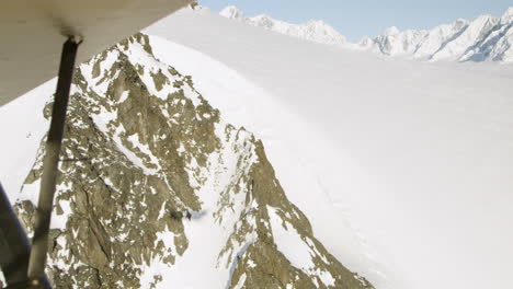 Aerial-fly-past-rocky-snow-covered-mountain