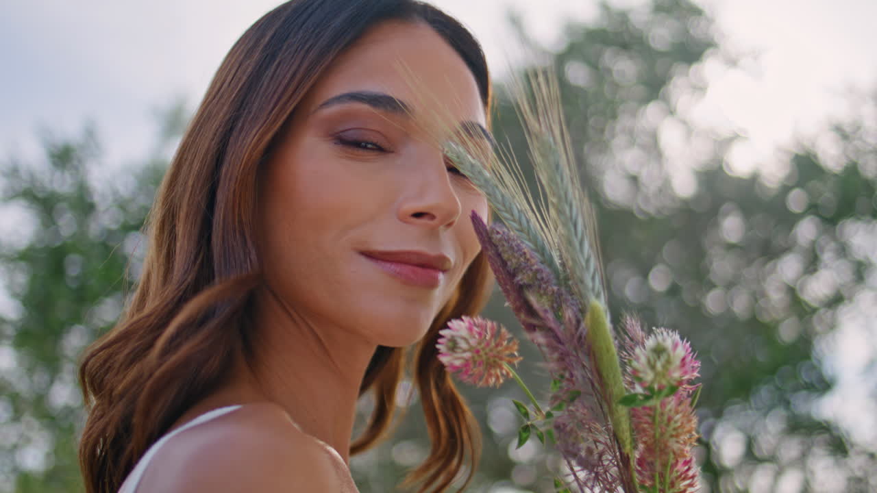 Señora serena admirando un ramo de espiguillas en un retrato de la naturaleza. Mujer disfrutando de las flores