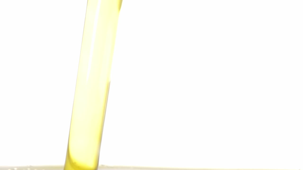 A pleasant flow of yellow olive oil falling in a transparent container, with nice rising air bubbles