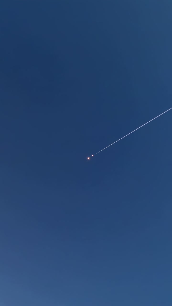 Vertical video: Streak entering, two bright lights moving across blue sky, trailing thin streak