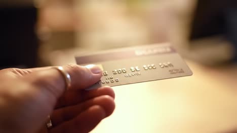 a close-up view of a hand holding a credit card, capturing the details and textures of both the card and the hand in a softly lit setting