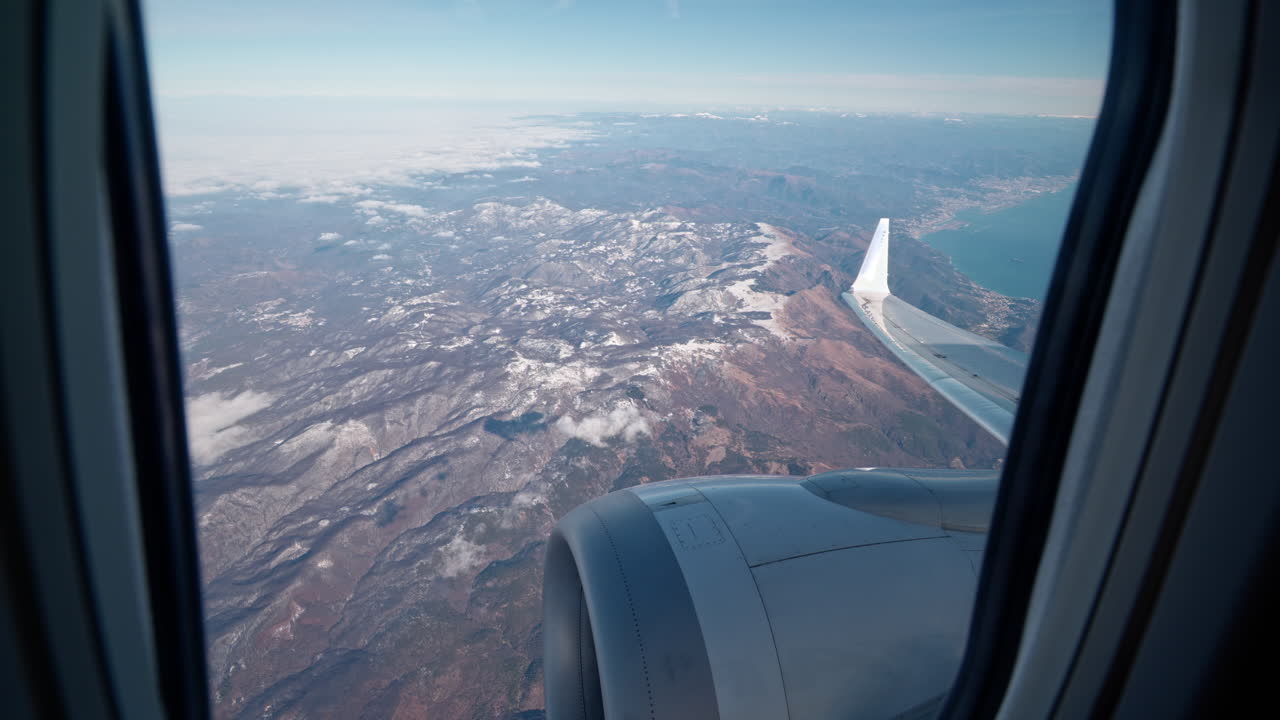 Flugzeugansicht über verschneite Berge, klarer Himmel, Reiseabenteuer