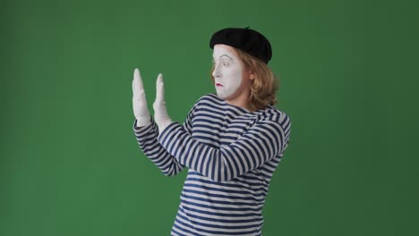 male mime artist pushing over green background