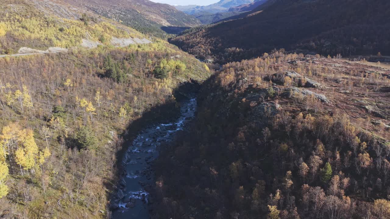 Mountain river flows trough a autumn colored valley in Jotunheimen National Park. Drone footage