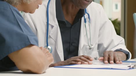 Mid-Section-Two-Medical-Professionals-Having-Meeting-In-Office-Space