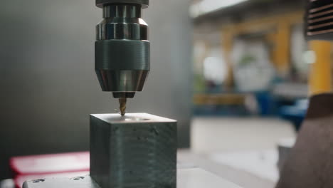 A-short-drill-bit-working-on-a-block-of-metal-in-a-car-production-factory