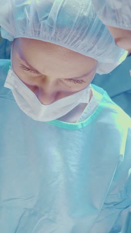 medical professional in surgical attire focused on performing a procedure in a sterile environment