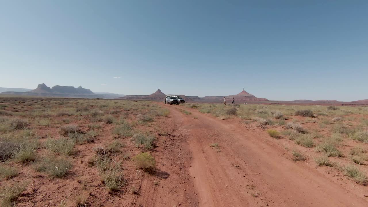 vista aérea de diversas personas en un sendero pavimentado de rocas rojas en un día soleado disfrutando de una aventura escénica con pirámides de piedra del desierto al fondo