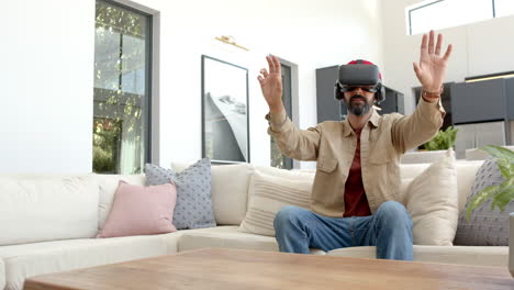 using vr headset, man sitting on sofa and interacting with virtual environment
