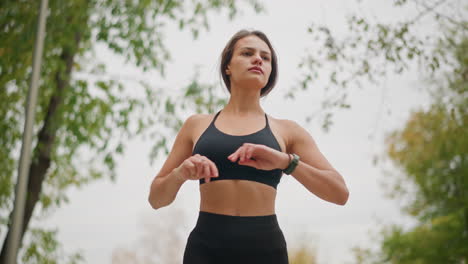 sport woman performing body exercise outdoors, stretching and strengthening body in a park with trees in the background, promoting a healthy lifestyle and physical fitness