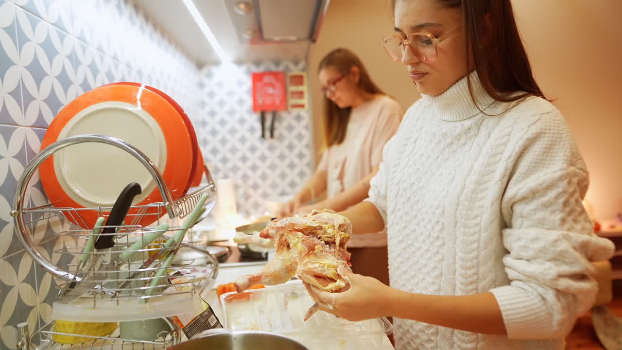mujeres jóvenes preparando pollo en una cocina