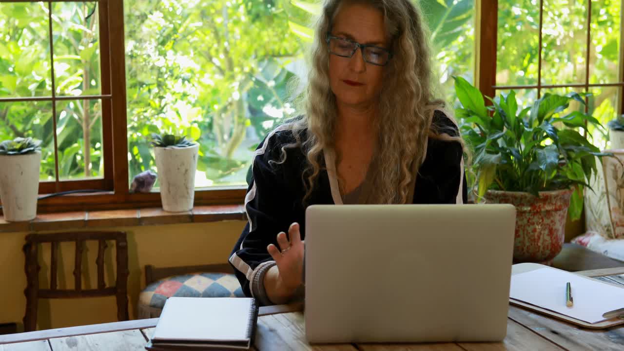 Reife Frau nutzt Laptop zu Hause 4K